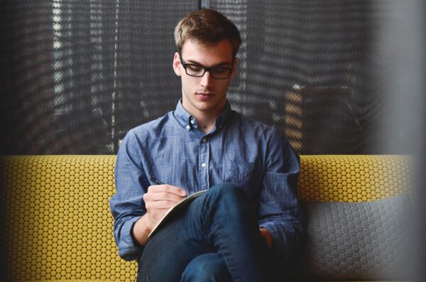 Man sitting on yellow couch writing content